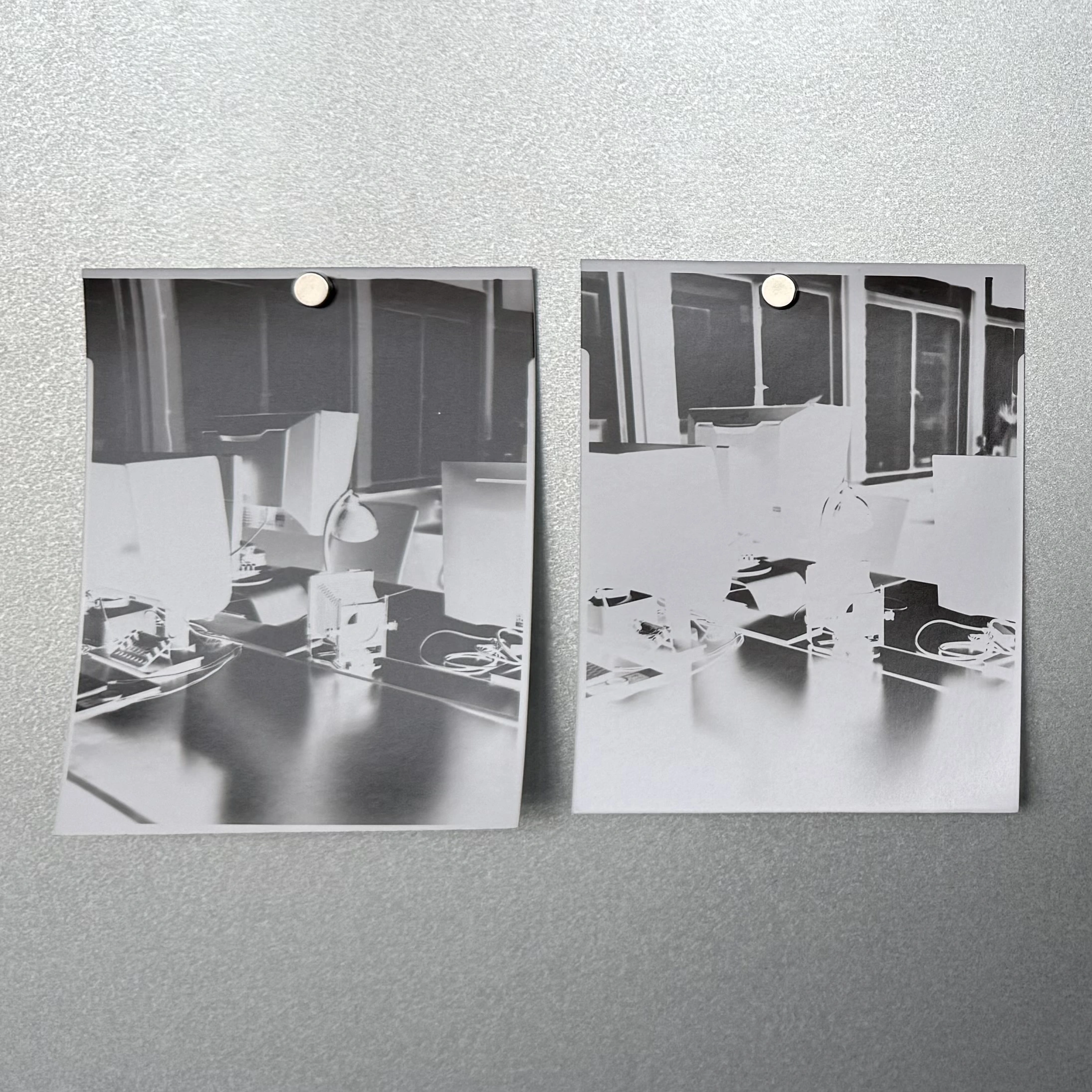 Two paper negatives pinned to a wall, showing the same scene of a table and chairs - one darker, one lighter, demonstrating different exposure choices